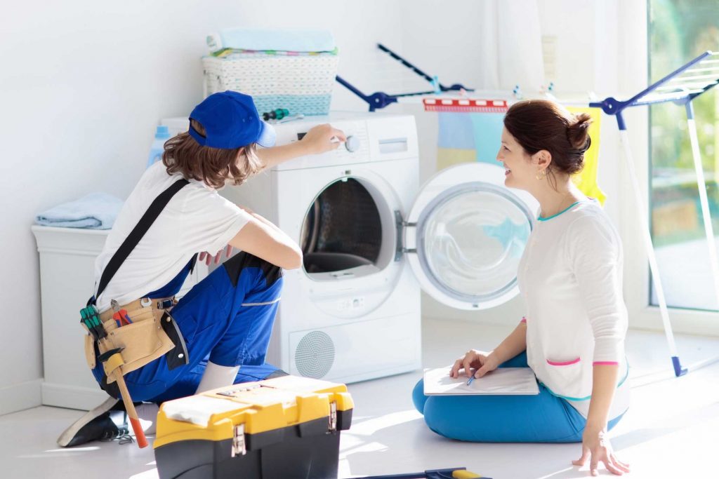 a technician repairing a washer while woman is watching - appliance repair service Camden